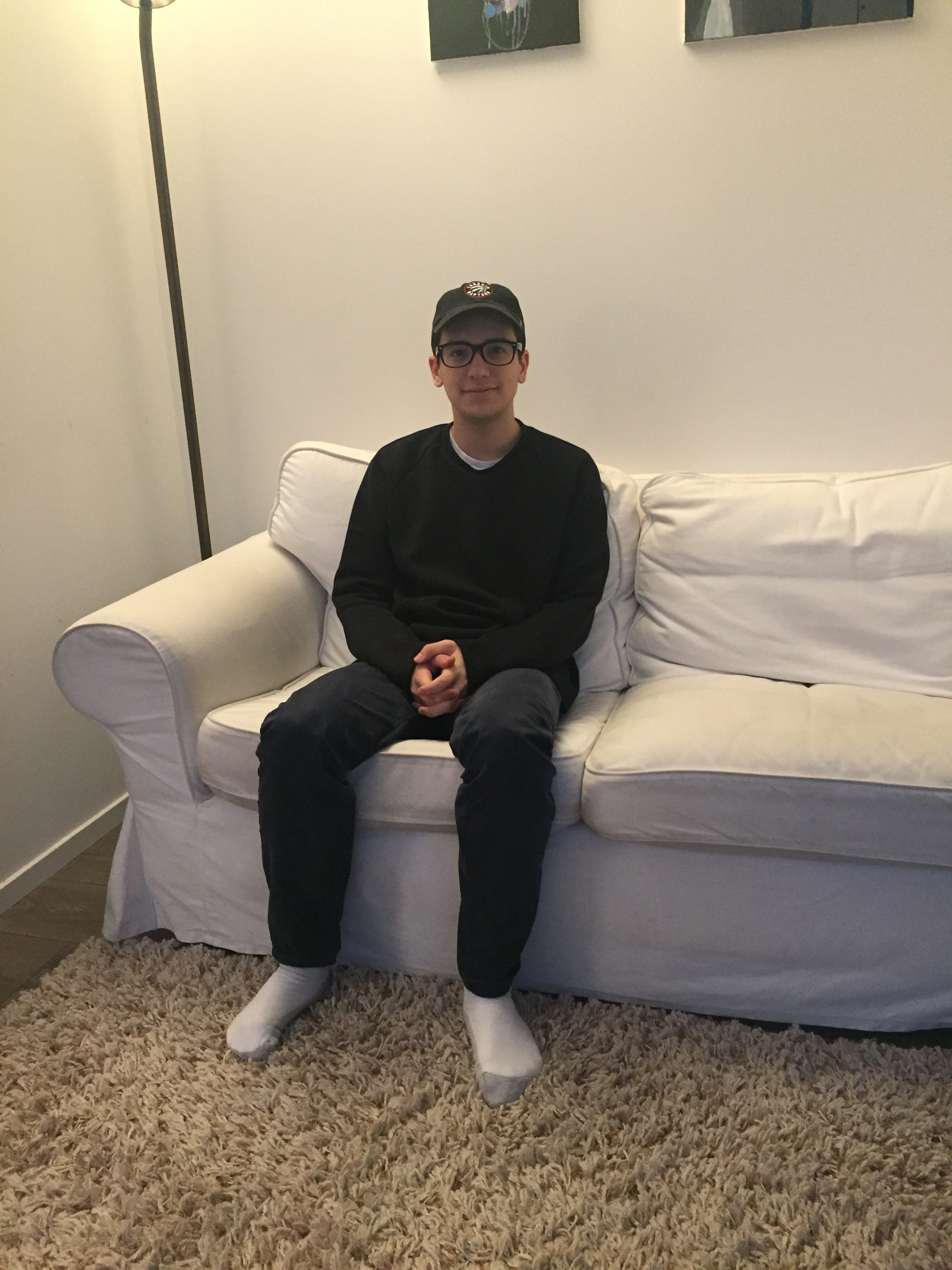Musician Lucas DiPasquale sits on a white couch.