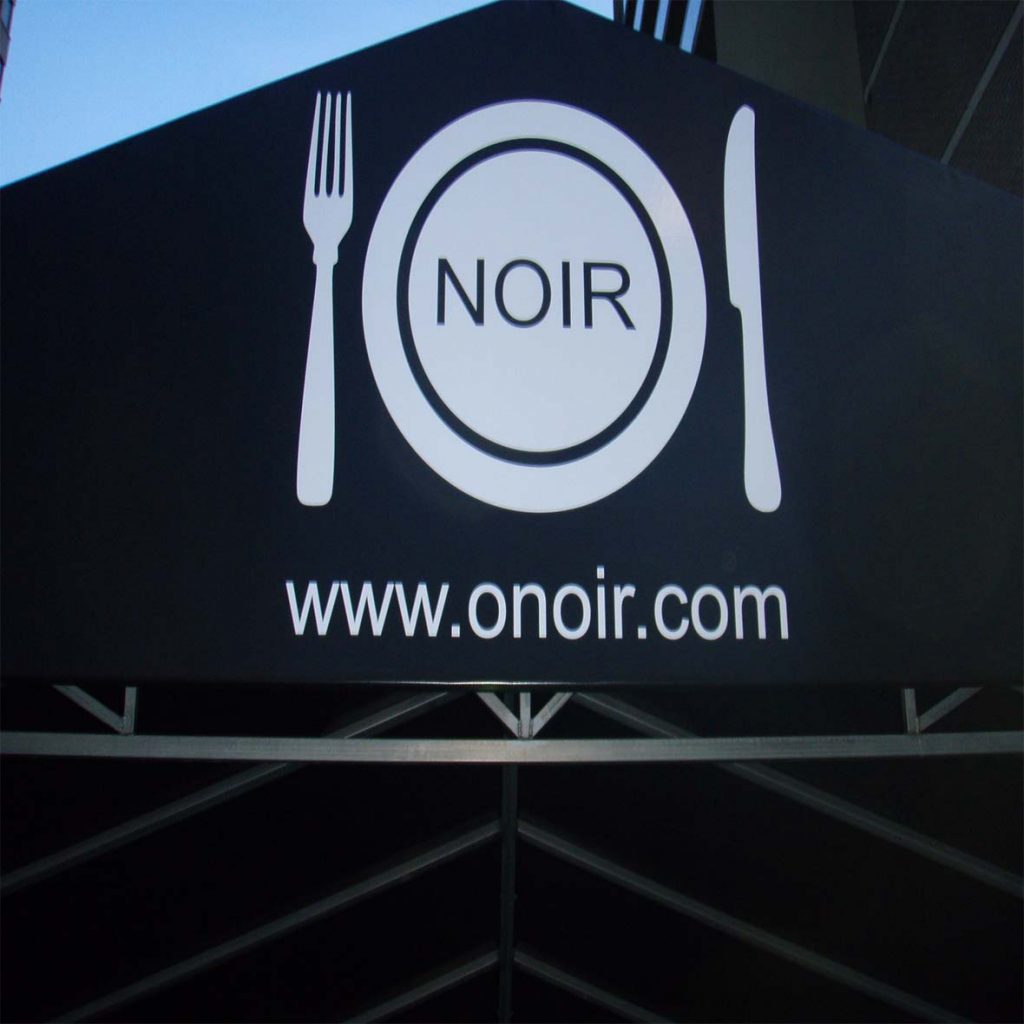 Black triangular sign with fork, knife and dish that says "ONOIR" and www.onoir.com under.
