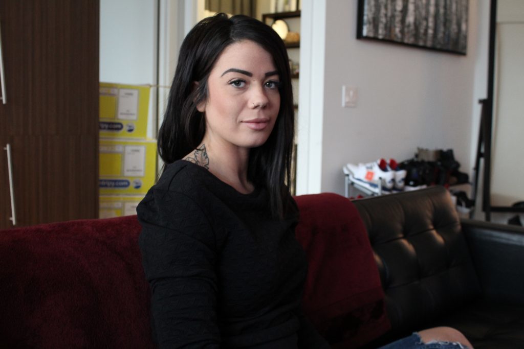 Laura Hesp seated on red couch looking at camera.