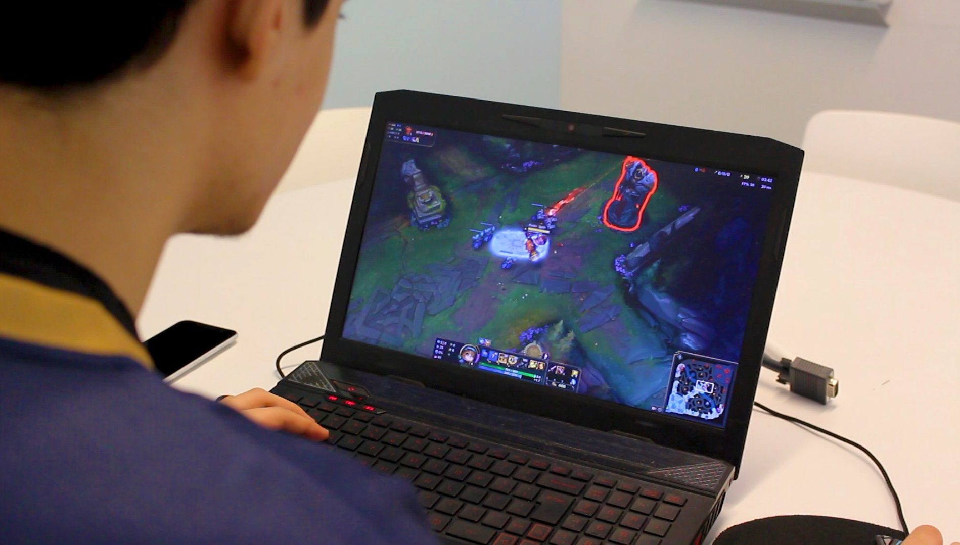 Back of man playing League of Legends on laptop.