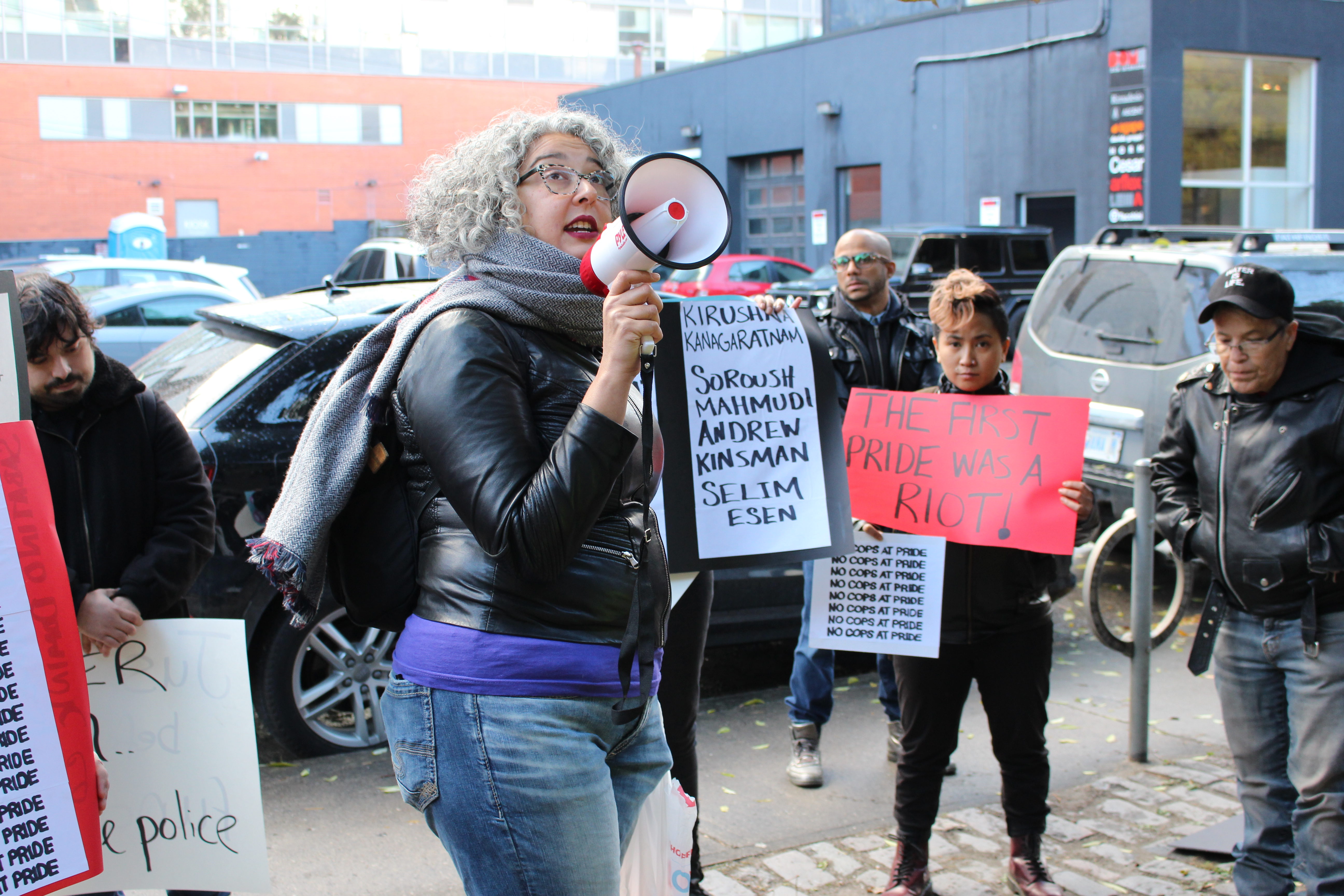 Woman with microphone surrounded by people holding signs.