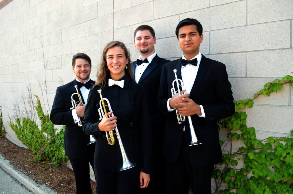 Four men and woman in bowties holding trumpets.