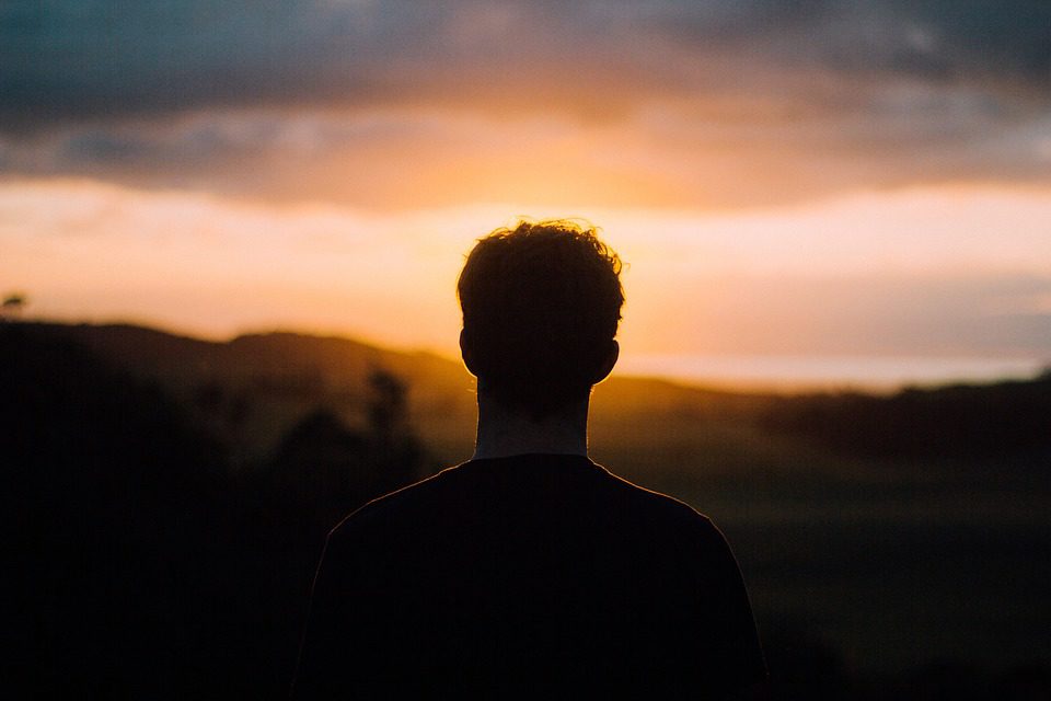 Silhouette of man looking towards sunset.