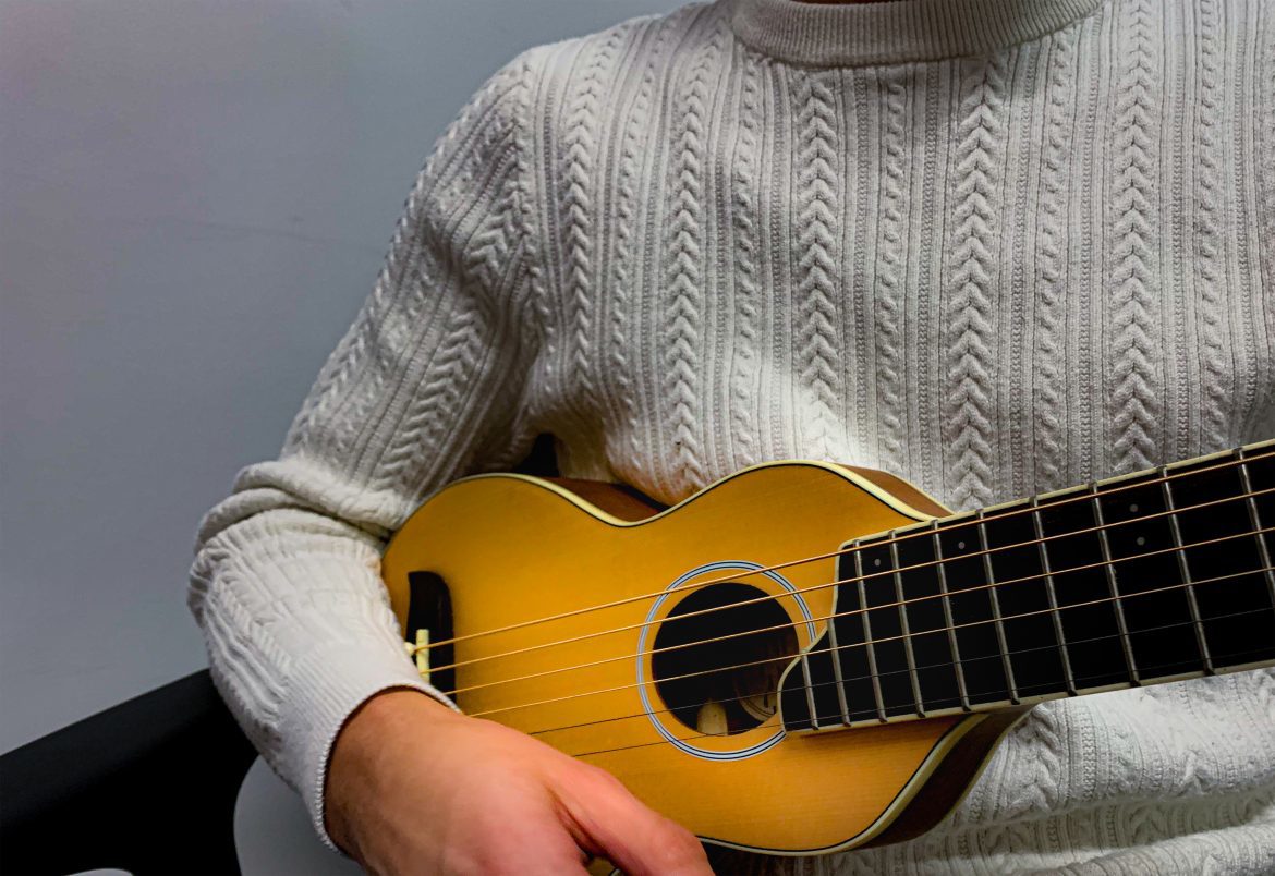 Closeup of a person's holding a guitar.