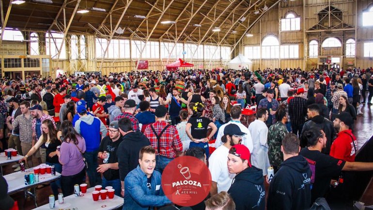 A crowd of people playing beer pong