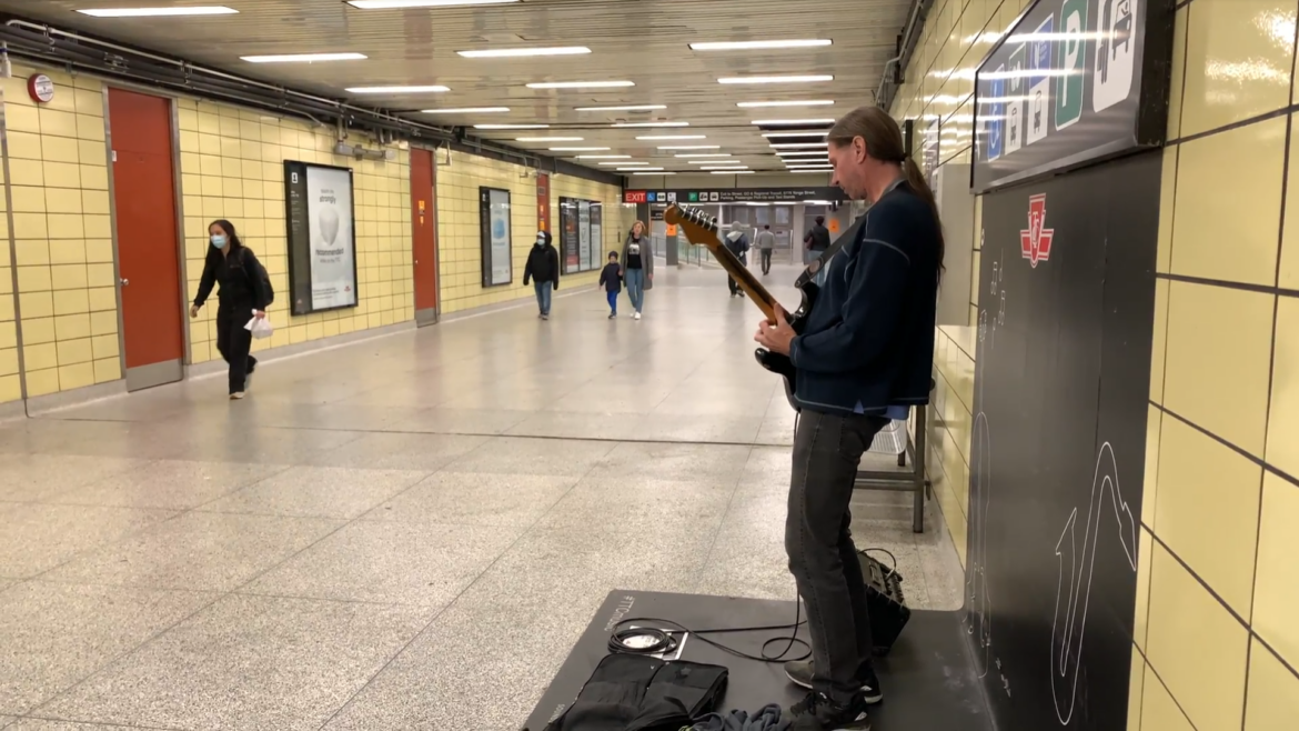 Mr. Finch plays his guitar in front of passing commuters.
