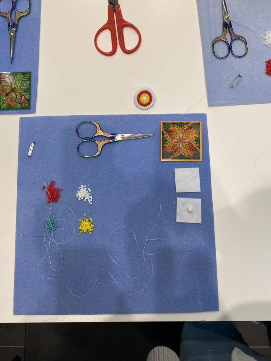 A blue tablecloth holding beads, scissors, and other beading materials