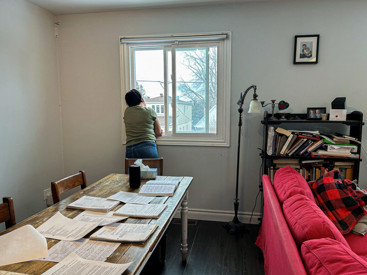 Women looking outside of window with her eating disorder research laid out on her dining table.