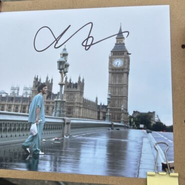 A signed photo of Cillian Murphy as Jim from 28 Days Later, walking alone across Westminster Bridge in London with Big Ben and the Houses of Parliament in the background on a deserted, rain-soaked street.