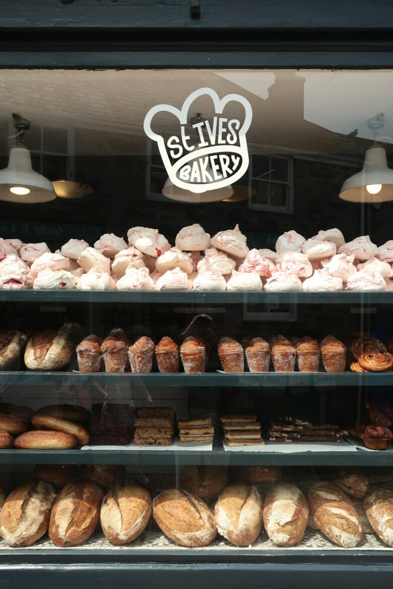 Bakery storefront window displaying rows of fresh pastries and bread, with a “Slives Bakery” logo above shelves filled with meringues, croissants, cakes, and loaves.